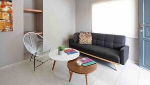 A modern living room with a black sofa, a white chair, and a round coffee table. - Meridia  2 (Yucatan Merida)