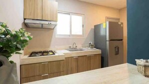 A modern kitchen with wooden cabinets, a stainless steel refrigerator, and a window providing natural light. - Meridia  2 (Yucatan Merida)