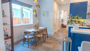 Una cocina moderna con comedor, sillas de madera, una mesa y una planta en maceta.