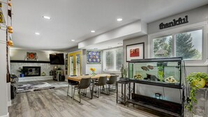 Un salon moderne comprenant un coin repas, un grand aquarium et un panneau décoratif sur le mur avec le mot « merci ».