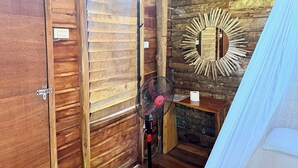 A wooden cabin room with a sliding door, a wall-mounted mirror, a fan, and a tent-like structure. - Payag n' Kapitan, Experience Pinubre Living (Siquijor)