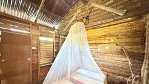 A rustic wooden room with a bed under a mosquito net, a wooden ceiling, and a rustic decor. - Payag n' Kapitan, Experience Pinubre Living (Siquijor)