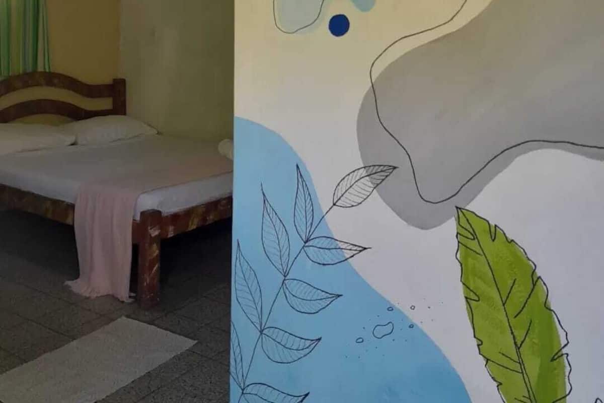 A room with a bed, a wooden headboard, and a wall with a colorful abstract design.