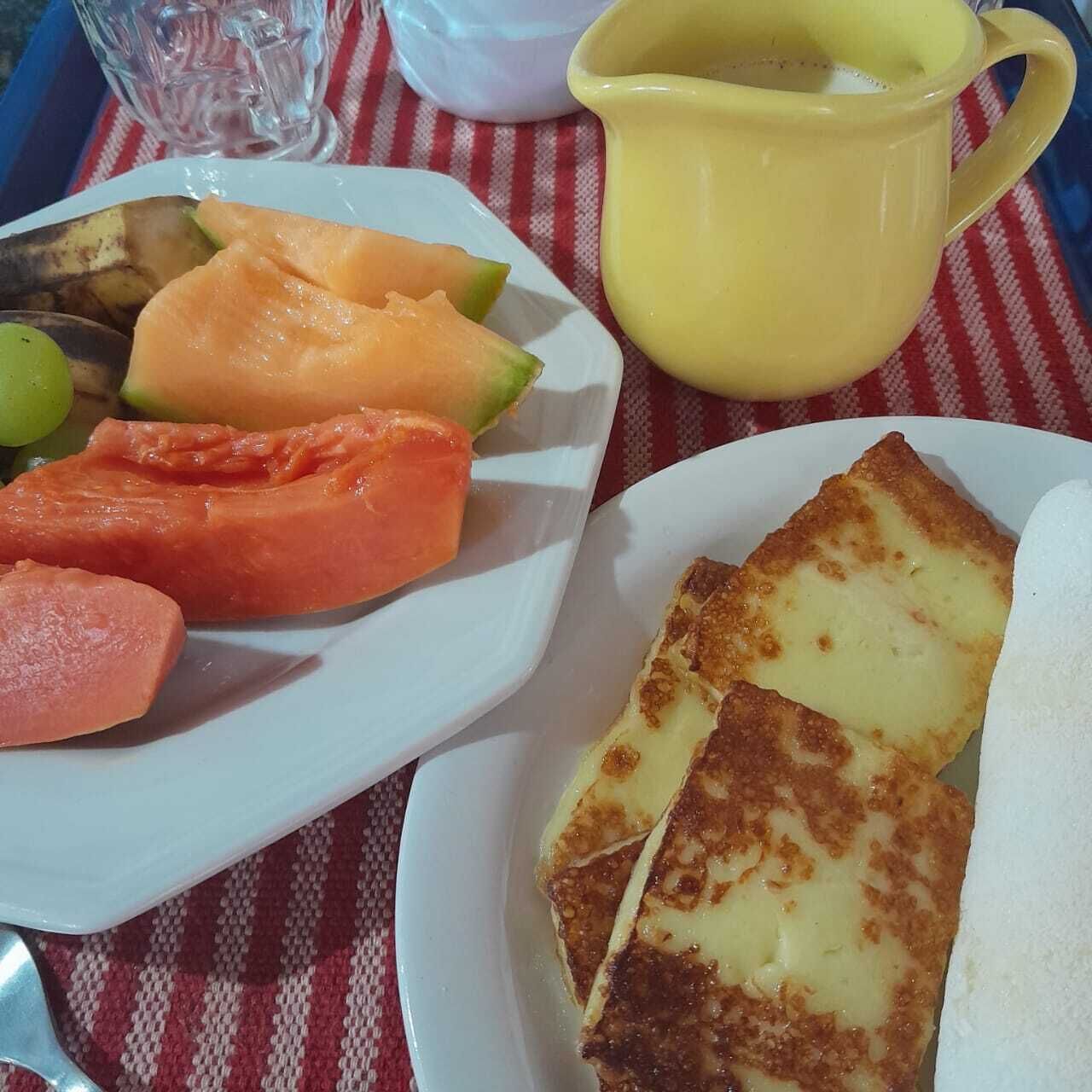 A plate with sliced fruits and a yellow pitcher, likely containing a beverage, on a checkered tablecloth.