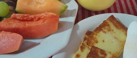 A plate with sliced fruits and a yellow pitcher, likely containing a beverage, on a checkered tablecloth.