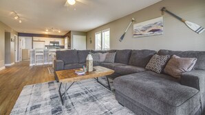 A spacious living room with a gray sectional sofa, a wooden coffee table, and a gray rug. - Osage Beach Condo w/ Private Deck & Lake Views! (Osage Beach)