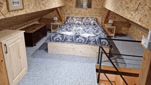 A cozy attic bedroom with a sloped ceiling, a wooden bed with a heart-shaped towel, a small wooden cabinet, and a framed picture on the wall. - Cottage with whirlpool and sauna (Stara Gora)