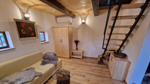 A cozy living room with a wooden staircase, a sofa with a fur throw, and a painting on the wall. - Cottage with whirlpool and sauna (Stara Gora)