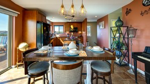 A dining area with a wooden table set for four, a piano, and a globe on a chair.