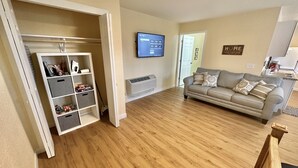 A living room with a grey sofa, a TV mounted on the wall, and a storage unit with grey bins. - Hot Tub Cozy Cottage in Colorado Springs (Colorado Springs)