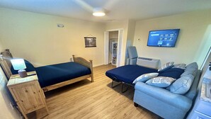 A bedroom with two single beds, a desk with a lamp, a TV, and a sofa. - Hot Tub Cozy Cottage in Colorado Springs (Colorado Springs)