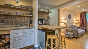 A compact kitchen with a wooden countertop, a built-in oven, and a dishwasher. There is a dining area with a grey sofa and two bar stools. - Grandma's House LA 1-bedroom apartment just 22 minutes to Lake Michigan (Lake Ann)