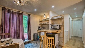 A compact kitchen with a dining area, wooden stools, a built-in microwave, and a coffee machine. - Grandma's House LA 1-bedroom apartment just 22 minutes to Lake Michigan (Lake Ann)