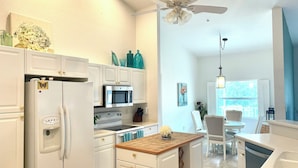 A compact kitchen with white cabinetry, a microwave, a stove, and a ceiling fan. - Bright, Safe, Comfortable 3Bdrm in Bradenton, FL.  Pool, Tennis, Golf,  Beaches. (Bradenton)