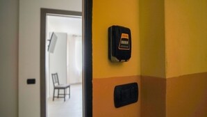 Una porta amb un tancament de codi, una cadira i un aparell fixat a la paret.