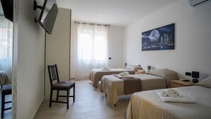 Habitació d'hotel amb dos llits, un televisor fixat a la paret, un quadre d'una vista urbana i una cadira.