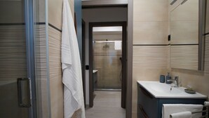 Un bany modern amb una cabina de dutxa de vidre, un lavabo i un suport per a tovalloles.