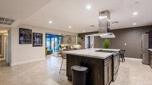 A modern kitchen with a central island, stainless steel appliances, and a dining area with a view to the outdoors. - Closest Walk to Old Town, Entertainment District (Scottsdale)