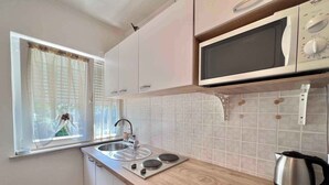 Une cuisine avec une fenêtre, un évier, une cuisinière, un four à micro-ondes et une bouilloire.