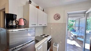 Eine kleine Küche mit Edelstahlkühlschrank, Kaffeemaschine, Wasserkocher und Spüle.