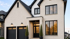 A modern two-story house with a garage, large windows, and a well-maintained lawn.