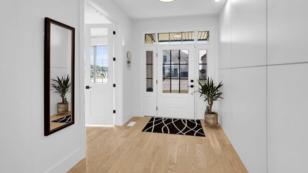 A hallway with a wooden floor, white walls, a large mirror, and two potted plants. - Brand New Modern Luxury Villa (London)