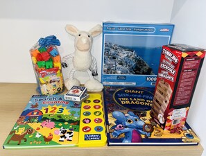 A variety of children's toys and books, including a puzzle, a stuffed animal, and a book titled 'Giant Seek-and-Find the Land of Dragons'. - Brand New Modern Luxury Villa (London)
