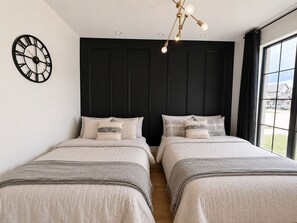 Un dormitorio con dos camas, un reloj de pared y una ventana con vistas.