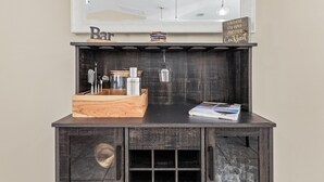 A bar area with a wooden counter, a wine glass, and a sign that reads "I believe I'll have another cocktail." - Bikes, Kayaks, Poker, Shuffleboard, Gulf Access, Heated Pool - Comfort on the H2O - Roelens (Cape Coral)