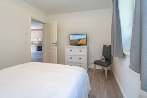Een slaapkamer met een bed, een dressoir, een televisie en een stoel.
