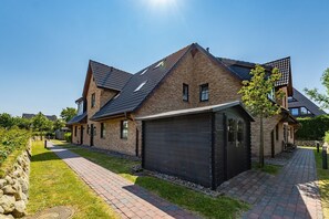 Uma casa moderna de dois andares com fachada de tijolo, porta de garagem escura e calçada pavimentada.