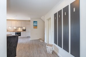 Een moderne keuken met witte kasten en een zithoek met een grijze bank.