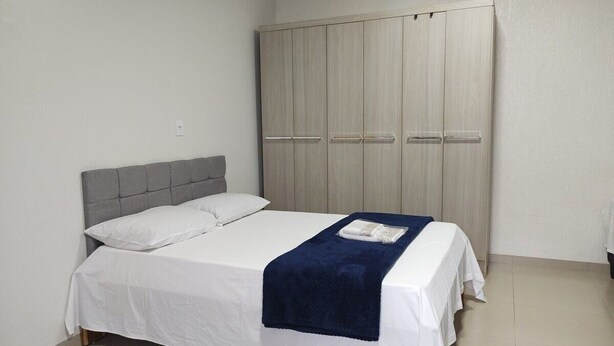 A bedroom with a bed, a grey headboard, a wardrobe, and a blue blanket.
