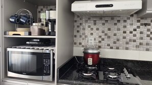 A kitchen with a microwave, a red slow cooker, a gas stove, and a coffee maker.