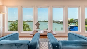 Ein Zimmer mit Blick auf eine Marina, ein Holztisch mit dekorativem Mittelstück und blau gepolsterte Sessel.