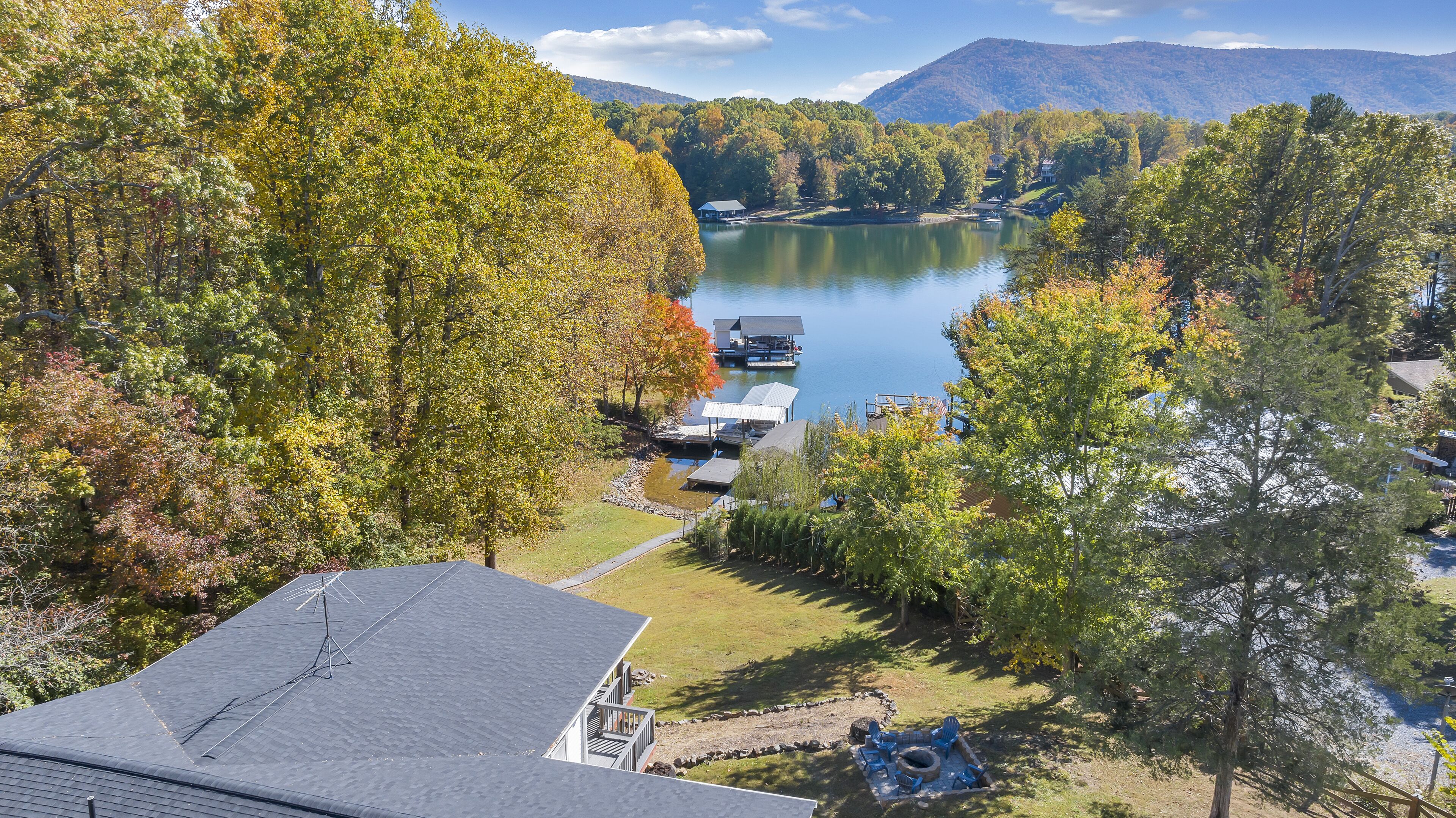 A lakeside property with a dock, a small building, and a grassy area with outdoor seating.
