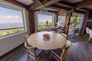 Enjoy meals in this cozy dining area with a round table, comfortable chairs, and a stunning mountain view.