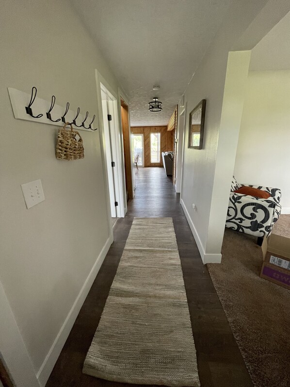 A hallway with a rug, a basket, and a couch. - Secluded Riverside Farmhouse - overlooks the Snake River. (Saint Anthony)