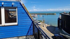 A blue-roofed building with a balcony overlooking a marina with boats.
