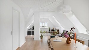 Ein geräumiger Loft mit hohen Decken, einem Holzespeise Tisch und Blick zum Himmel durch Dachfenster.
