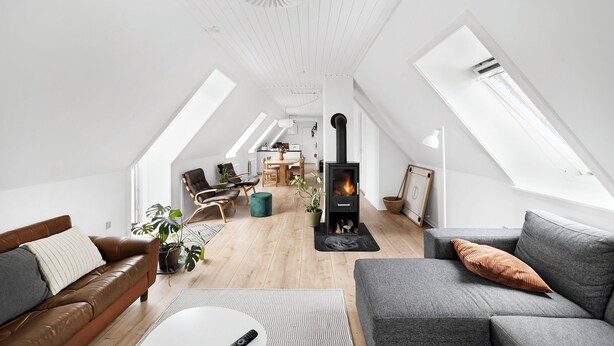 Ein Loft-Wohnzimmer mit Kamin, hohen Decken, Dachfenstern und modernen Möbeln.