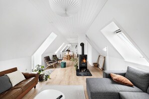 Ein Loft-Wohnzimmer mit Kamin, hohen Decken, Dachfenstern und modernen Möbeln.