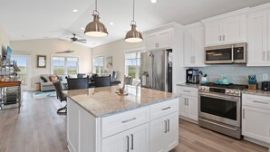 A spacious kitchen with white cabinets, stainless steel appliances, and a large island. - "DemmMarsh-Uns" is a 4 Bedroom, 3.5 Bathroom Home w/ a Private Pool and Elevator! (Holden Beach)