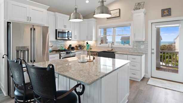 A modern kitchen with white cabinetry, stainless steel appliances, and a large island with seating. - "DemmMarsh-Uns" is a 4 Bedroom, 3.5 Bathroom Home w/ a Private Pool and Elevator! (Holden Beach)