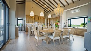Een moderne keuken met houten kastjes, een centraal eiland en een eethoek met rieten stoelen.