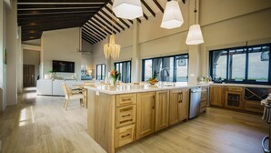 Een ruime keuken met houten kasten, een groot eiland en hanglampen.
