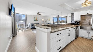 A modern kitchen with white cabinetry, a granite countertop, and a stainless steel sink.