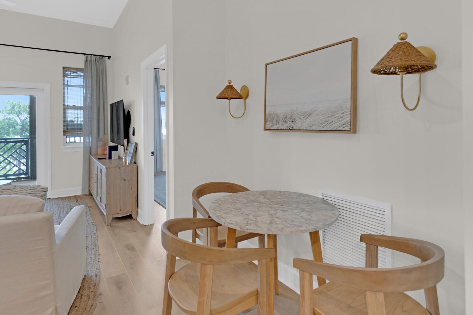 Un salon moderne avec une table ronde en marbre, des chaises en bois, un téléviseur et un tableau accroché au mur.