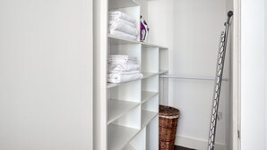 A white closet with shelves holding folded towels and a wicker basket. - Stunning 2BR in East London, nr Old Street stasion, by Blueground (London)