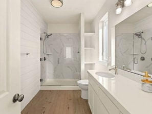 Une salle de bain moderne avec une douche à parois de verre, des toilettes et un meuble-lavabo avec un miroir.